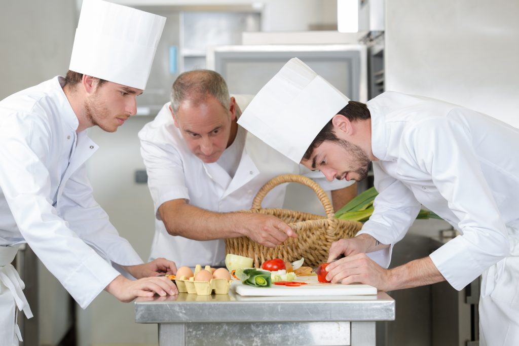 professional chef directiong assitant to prepare a dishe at restaurant
