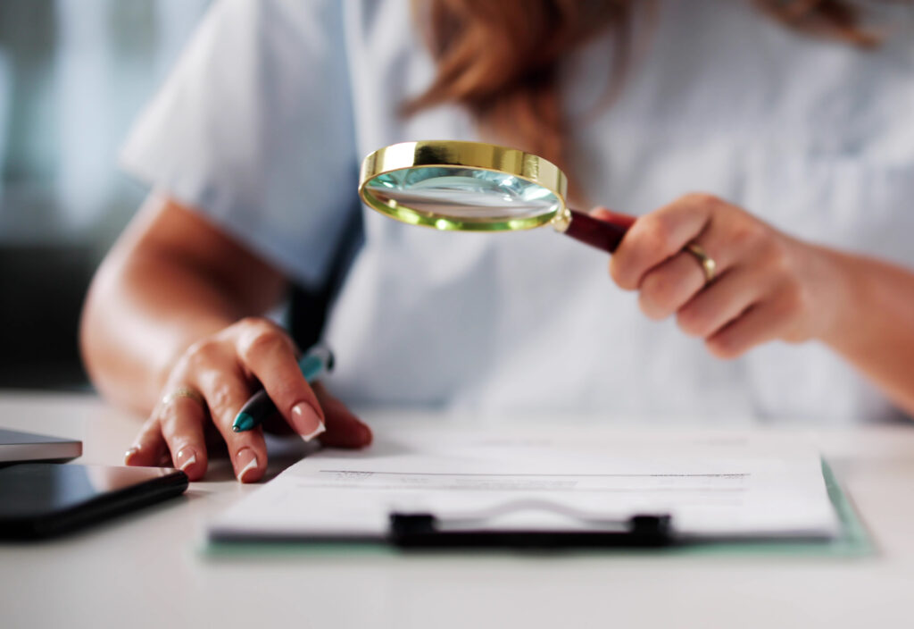 Femme analysant un document sur les prix en coiffure et esthétique avec une loupe