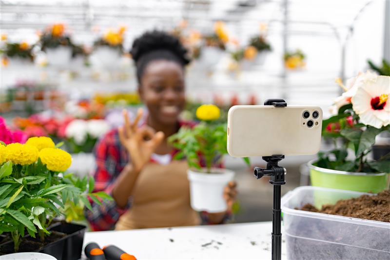 Fleuriste créant du contenu pour les réseaux sociaux en filmant ses compositions florales dans sa boutique.