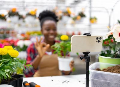 Fleuriste créant du contenu pour les réseaux sociaux en filmant ses compositions florales dans sa boutique.
