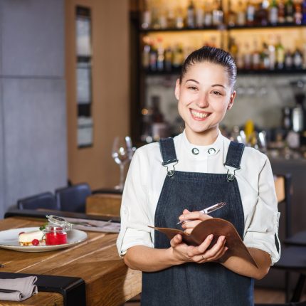 Jeune-femme serveuse prenant la commande d'un couple dans un restaurant dans le cadre d'un service en salle.