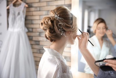 Makeup artist preparing bride before her wedding in room