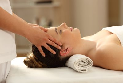 Side view portrait of a woman relaxing receiving a facial massage in a spa salon