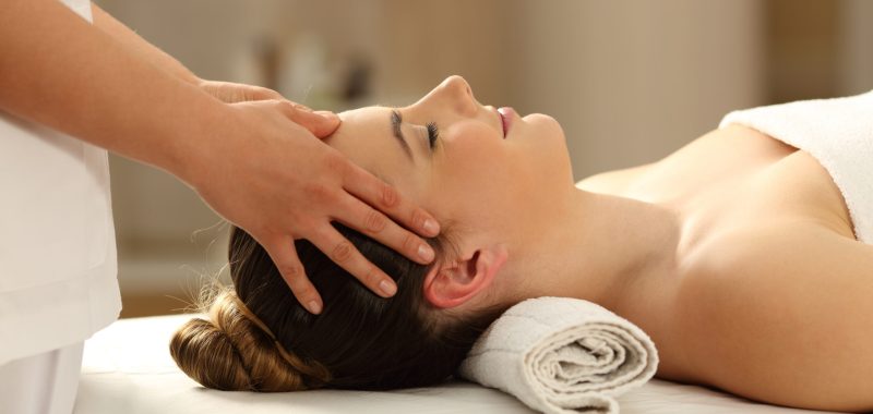 Side view portrait of a woman relaxing receiving a facial massage in a spa salon