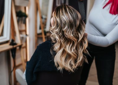 Beautiful hairstyle of young woman after dyeing hair and making highlights in hair salon.