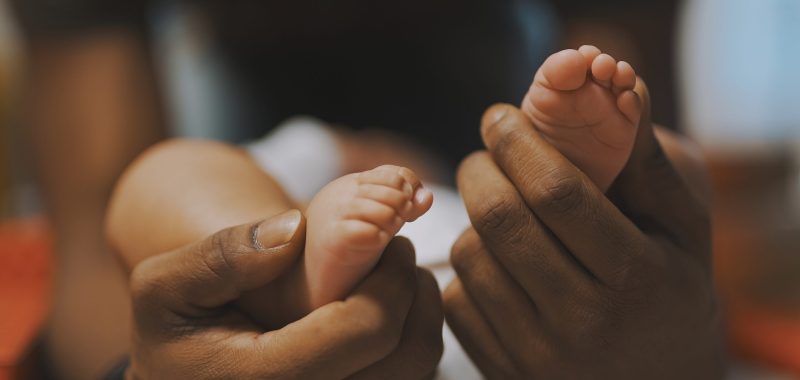 Black father playing with baby feet. Close up. High quality photo