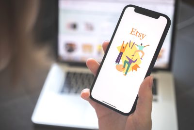 Kharkov, Ukraine - August 12, 2021: Etsy app. Woman using smartphone with etsy application. Brand logo