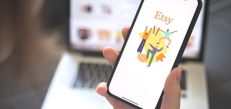 Kharkov, Ukraine - August 12, 2021: Etsy app. Woman using smartphone with etsy application. Brand logo