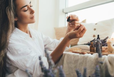 Young woman applying natural organic essential oil on hair and skin. Home spa and beauty rituals. Skin care.