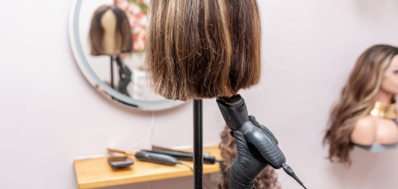 cutting the wig on the mannequin head by electric trimmer