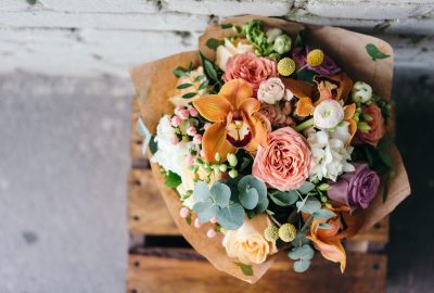 Bouquet de fleurs coloré mêlant roses, orchidées et feuillages, exemple de compositions florales tendances.