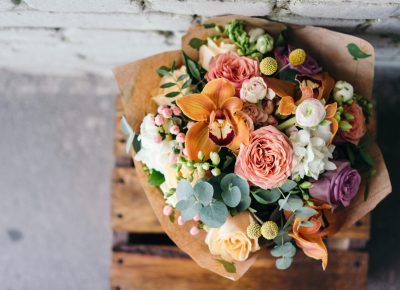 Bouquet de fleurs coloré mêlant roses, orchidées et feuillages, exemple de compositions florales tendances.
