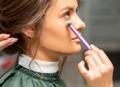 Makeup and hairstyle process. Makeup artist and hairdresser preparing young caucasian woman, working in tandem