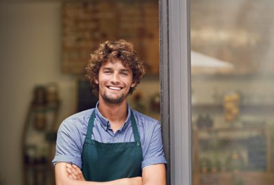 Management, arms crossed and portrait of man at restaurant as small business owner, coffee shop or waiter. Entrepreneur, happy and smile with professional male barista at front door of cafe and diner.