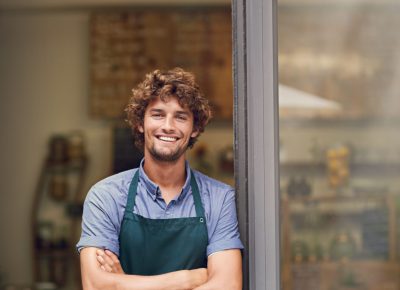 Management, arms crossed and portrait of man at restaurant as small business owner, coffee shop or waiter. Entrepreneur, happy and smile with professional male barista at front door of cafe and diner.