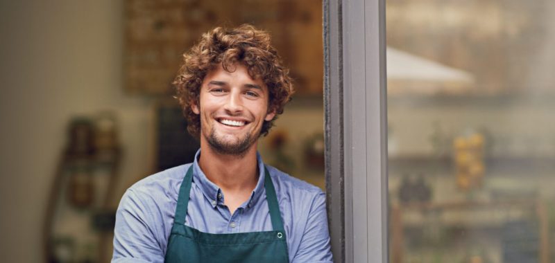 Management, arms crossed and portrait of man at restaurant as small business owner, coffee shop or waiter. Entrepreneur, happy and smile with professional male barista at front door of cafe and diner.