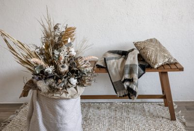 Décoration de Noël scandinaves avec une composition florale en matériaux naturels, banc en bois, plaid et coussin pour une ambiance chaleureuse.