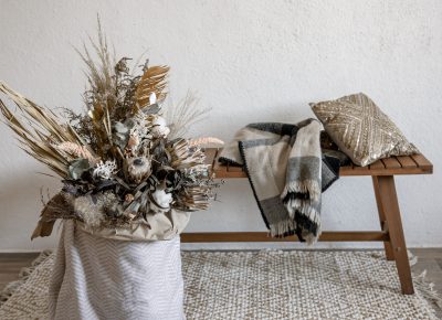 Décoration de Noël scandinaves avec une composition florale en matériaux naturels, banc en bois, plaid et coussin pour une ambiance chaleureuse.