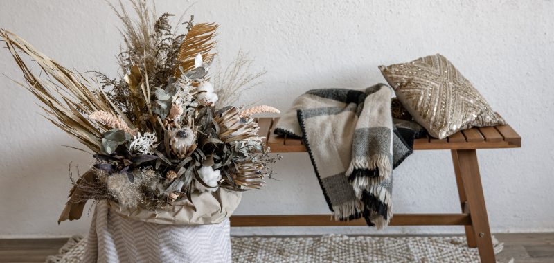 Ambiance Noël scandinaves déco nature et artisanale Décoration de Noël scandinaves avec une composition florale en matériaux naturels, banc en bois, plaid et coussin pour une ambiance chaleureuse.