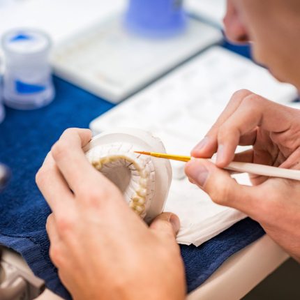 Dental technician or dentist working with tooth dentures in his laboratory