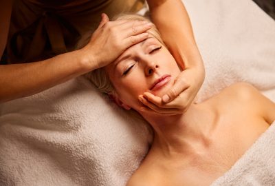Femme recevant un massage Kobido du visage, soin anti-âge japonais favorisant relaxation et jeunesse de la peau.