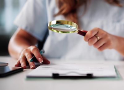 Femme analysant un document sur les prix en coiffure et esthétique avec une loupe